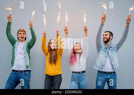 Gruppo di amici multietnici che brilla con gli sparklers - gente che balla Con sparklers nelle mani - corto colpo di giovane ragazzi che tengono le luci del bengala a. Foto Stock