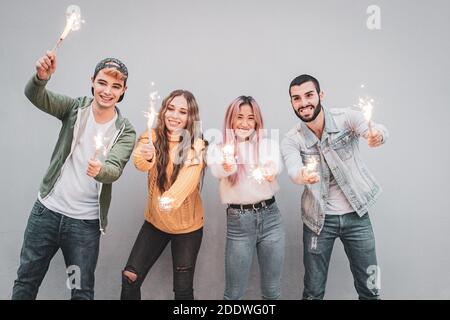 Gruppo di amici multietnici che brilla con gli sparklers - gente che balla Con sparklers nelle mani - corto colpo di giovane ragazzi che tengono le luci del bengala a. Foto Stock