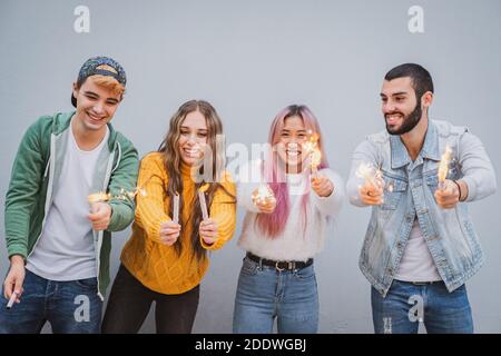 Gruppo di amici multietnici che si accalcano con sparklers - quattro teneegers festa con gli sparklers nelle loro mani Foto Stock