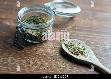 un mestolo di legno e un vaso di vetro con origano essiccato Foto Stock