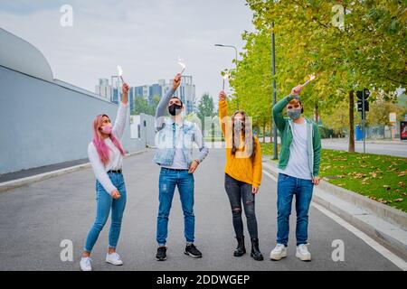 Gruppo di amici multietnici che si accecano con gli sparklers e indossano il viso maschere di sicurezza mantenendo la distanza sociale durante il tempo di coronavirus - Covid-19 spr Foto Stock