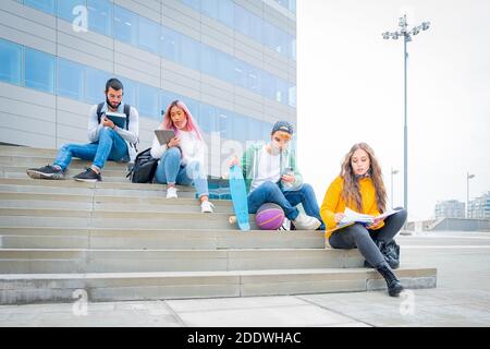 Giovani studenti universitari durante la pandemia del coronavirus. Quattro studenti universitari multi-etnici con maschere protettive all'aperto Foto Stock