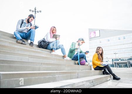 Giovani studenti universitari durante la pandemia del coronavirus. Quattro studenti universitari multi-etnici con maschere protettive all'aperto Foto Stock