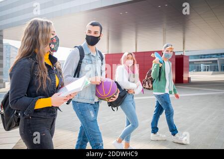 Studenti multirazziali con maschera facciale che cammina indossando maschera protettiva Durante la pandemia codvid19 al campus universitario - nuovo stile di vita normale con così Foto Stock