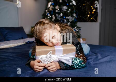 La ragazza carina piccola ha ricevuto il regalo di festa. Divertiti a ricevere regali. Bambino eccitato circa disimballare il suo regalo. Natale, vacanze e concetto di infanzia Foto Stock