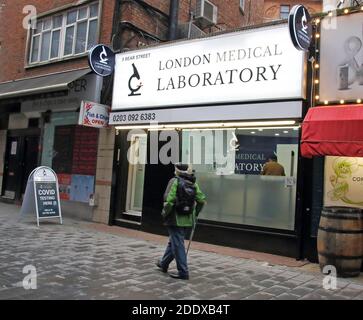 Londra, Regno Unito. 25 Nov 2020. Un uomo cammina oltre un Covid 19 Testing Lab fuori Leicester Square.IT è stato annunciato che Londra è di rimanere nel Tier due dopo che l'attuale blocco termina il 2 dicembre. L'intera Inghilterra tornerà ad essere un sistema Tier, con la maggior parte del paese di livello due con restrizioni più elevate rispetto a prima. Vaste aree delle Midlands e del Nord si recheranno al livello 3, dove, sebbene i negozi al dettaglio non essenziali possano aprire, i Pub e i ristoranti possono eseguire un servizio di take-away solo nel periodo che va fino a Natale. Credit: SOPA Images Limited/Alamy Live News Foto Stock