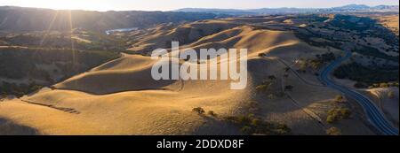 La luce del sole dorata splende sulle colline ondulate della California del Nord. Queste belle colline erose diventano verdi una volta che l'inverno porta pioggia stagionale. Foto Stock