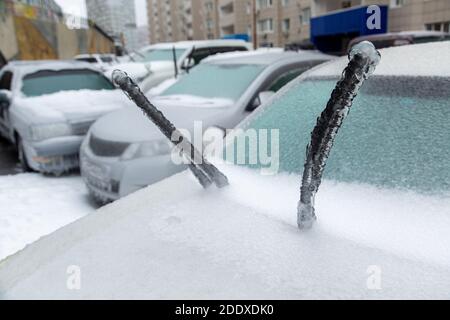 I panni di un'auto bianca sono molto ghiacciati a causa della neve bagnata in inverno. Bloccato da ghiaccio. Foto Stock