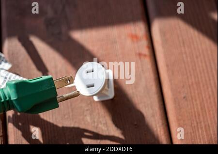 Uso tipico di un adattatore di alimentazione elettrica a 3 poli da un cavo di alimentazione dotato di messa a terra a un cavo a 2 poli senza collegamento messa a terra Foto Stock