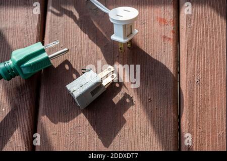 Uso tipico di un adattatore di alimentazione elettrica a 3 poli da un cavo di alimentazione dotato di messa a terra a un cavo a 2 poli senza collegamento messa a terra Foto Stock