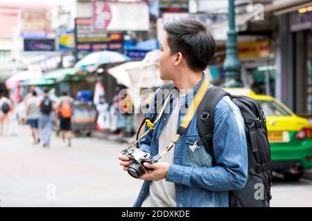 Asian male fotografo turistico backpacking in Khao san Road, Bangkok, Thailandia in vacanza Foto Stock