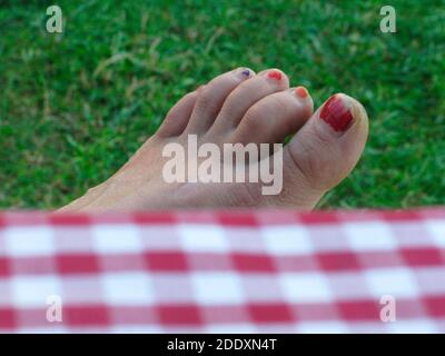 piede di una donna con unghie dipinte di rosso, a piedi nudi in estate Foto Stock
