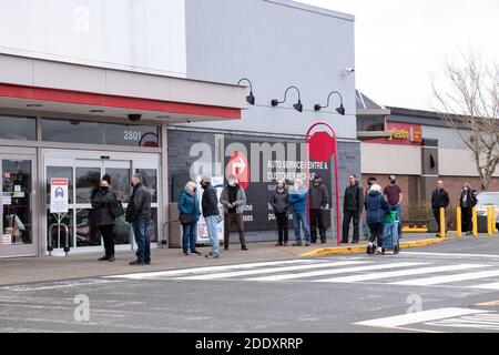 Courtenay, Canada - Nov 21,2020: Le persone si stanno allineando per entrare nel Canadian Tire Store praticando la distanza sociale tra di loro a causa di COVID-19. Foto Stock