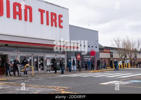 Courtenay, Canada - Nov 21,2020: Le persone si stanno allineando per entrare nel Canadian Tire Store praticando la distanza sociale tra di loro a causa di COVID-19. Foto Stock