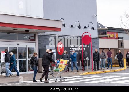 Courtenay, Canada - Nov 21,2020: Le persone si stanno allineando per entrare nel Canadian Tire Store praticando la distanza sociale tra di loro a causa di COVID-19. Foto Stock