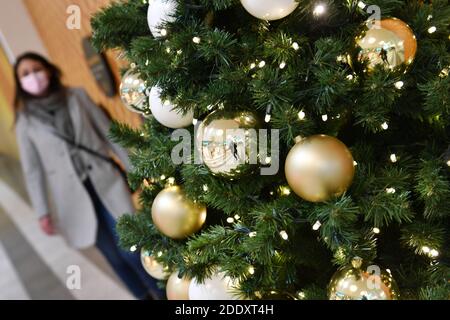 Quadro tematico i prigionieri nella pandemia del coronavirus il 26 novembre 2020. Una giovane donna con maschera facciale, la maschera passa davanti a un Weihaftertsbaum in un centro commerciale, centro commerciale. Pandemia, blocco, arresto, valore di incidenza. MODELLO RILASCIATO! | utilizzo in tutto il mondo Foto Stock