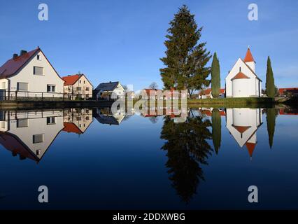 Saalau, Germania. 24 Nov 2020. La cappella sulla piazza del villaggio di Saalau, alberi e case si riflettono in uno stagno. Il villaggio nel nord del distretto di Bautzen nella Sassonia orientale appartiene alla città di Wittichenau dal 1994. Si trova nel paesaggio delle brughiera e degli stagni dell'alta Lusazia e fa parte dell'area degli insediamenti sorbiani. Credit: Robert Michael/dpa-Zentralbild/ZB/dpa/Alamy Live News Foto Stock