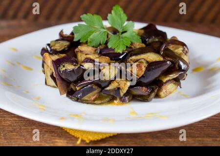 Piatto di melanzane a dadini su una crema di pomodori ciliegini gialli in un piatto bianco. Legno di fondo. Messa a fuoco selettiva. Foto Stock