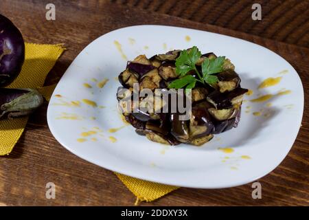 Piatto di melanzane a dadini su una crema di pomodori ciliegini gialli in un piatto bianco. Legno di fondo. Messa a fuoco selettiva. Foto Stock
