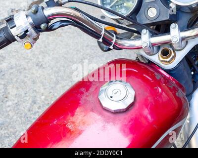 Frammento di un serbatoio di gas di una motocicletta rossa lucida con coperchio in argento e manubrio cromato. Foto di primo piano Foto Stock