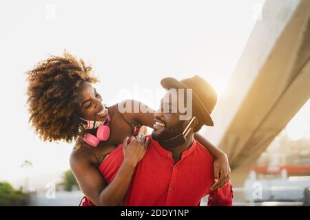 Felice coppia africana piggyback all'aperto durante la pandemia del virus corona - Concetto di relazione tra i giovani Foto Stock