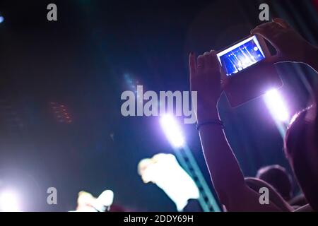 Un uomo di una sala da concerto spara una performance di scena su uno smartphone. Foto Stock