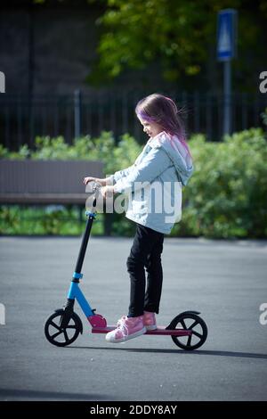 Sorridente bambina guida scooter nel parco. Spazio vuoto per il testo Foto Stock