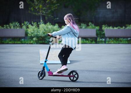 Sorridente bambina guida scooter nel parco. Spazio vuoto per il testo Foto Stock