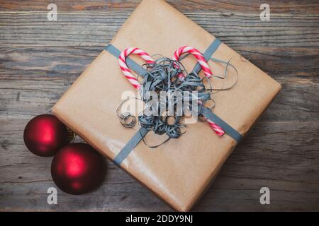 Scatola regalo di Natale marrone decorata con canne caramelle e nastro di avvolgimento arricciato. Foto Stock