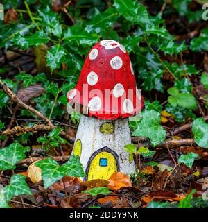 Esposizione artificiale infantile di un rosso e bianco agarico mosca fungo di casa di legno in un bosco di fata incantato toadstool durante il condimento autunnale Foto Stock