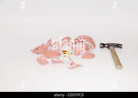 Banca piggy rotta con alcune monete accanto ad un martello isolato su sfondo bianco. Concetto di crisi. illustrazione 3d. Foto Stock