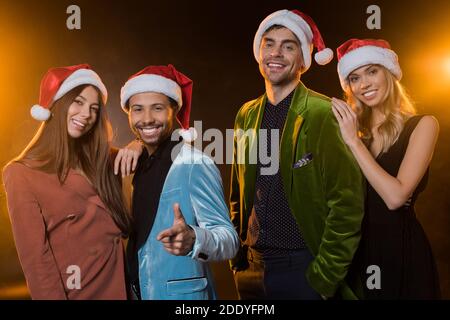 felici amici multiculturali a santa cappelli sorridenti su nero Foto Stock