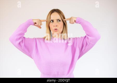 Immagine di giovane donna fare un gesto pazzo e vestito in felpa rosa casual. Su sfondo bianco Foto Stock