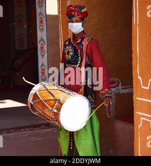 Indiano tradizionale uomo che indossa etnico rajasthani vestito suonare batteria o. dhol in un evento Foto Stock