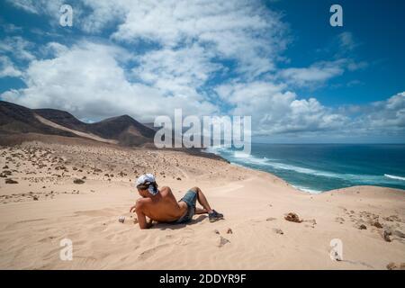 il giovane si riposa per guardare il paesaggio. Dune di Jandía . Fuerteventura. Isole Canarie Foto Stock