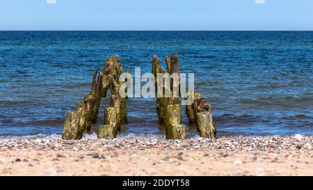 frangiflutti di legno sullo sfondo di mare calmo e sabbia Foto Stock