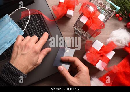 Concetto di persona che fa shopping di natale in linea a casa sicuro da covid-19 da un laptop. Vista dall'alto. Composizione orizzontale. Foto Stock