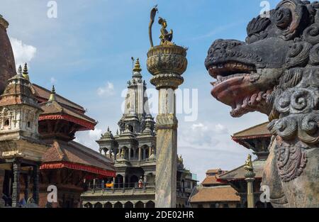 Templi e statue in Piazza Durbar a Patan in Kathmandu. Nepal. Il tempio sullo sfondo è il Krishna Mandir (Tempio di pietra). Sulla colonna è Foto Stock