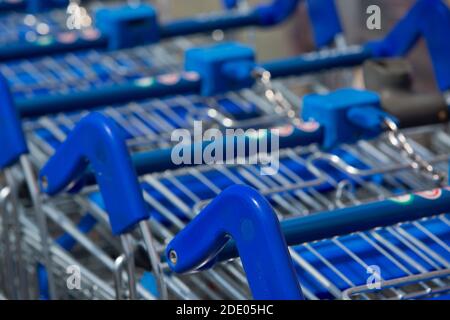 Primo piano di carrelli blu per supermercati pronti per l'uso all'esterno Un grande supermercato britannico in un parco al dettaglio Foto Stock