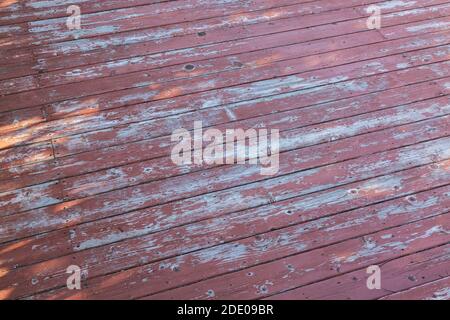 Primo piano di legno maroon colorato patio tavole in legno bisogno di un nuovo cappotto di vernice. Foto Stock