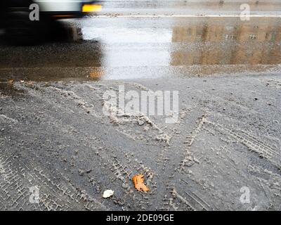la prima neve fusa sulla superficie della strada cittadina e. auto sfocata in movimento il giorno d'autunno Foto Stock