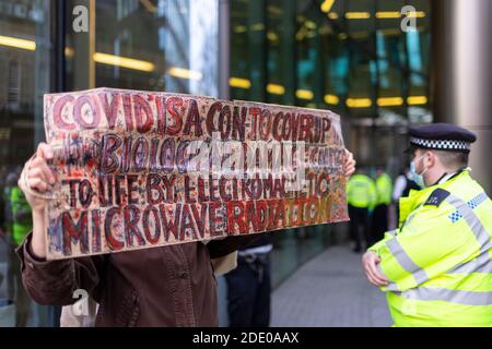 Manifestante che tiene la bandiera durante la protesta anti-vaccinazione, Bill e Melinda Gates Foundation Office, Londra, 24 novembre 2020 Foto Stock