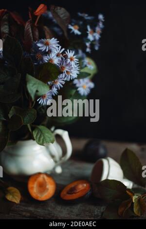 Bouquet di fiori da giardino in vaso di argilla vicino alla prugna Foto Stock