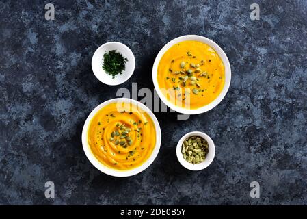 Purea di zucca in ciotola su sfondo di pietra blu con spazio libero per il testo. Concetto di alimentazione sana. Vista dall'alto, disposizione piatta Foto Stock