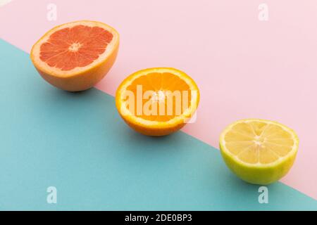 Pompelmo, arancia e limone su sfondo rosa e blu Foto Stock