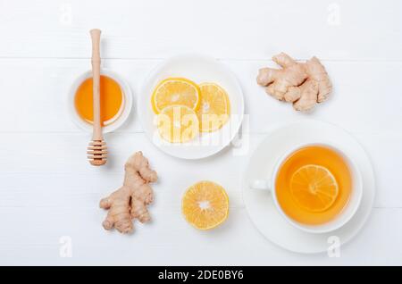 Zenzero con tè alle erbe al limonee su sfondo bianco di legno Foto Stock