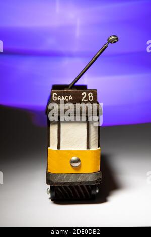 Piccolo modello in legno del tram giallo 28 di Lisbona con effetto luminoso sullo sfondo. Foto Stock