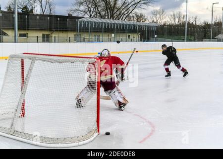 i giocatori di hockey dei giovani sparano su goalie durante l'hockey su ghiaccio all'aperto formazione Foto Stock