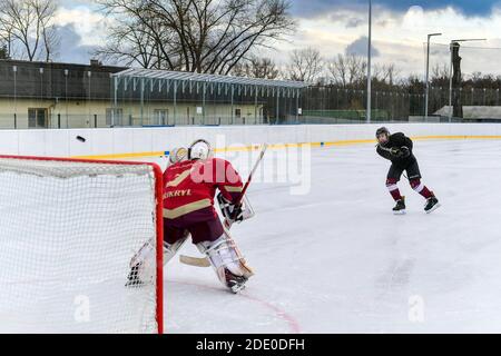 i giocatori di hockey dei giovani sparano su goalie durante l'hockey su ghiaccio all'aperto formazione Foto Stock