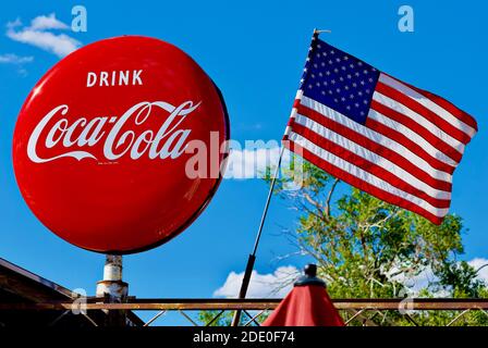 Seligman, Arizona, USA - 30 luglio 2020: Un cartello Coca-Cola 'Button' e la bandiera degli Stati Uniti volano sulla storica Delgadillo's Sno-Cap lungo la storica Route 66. Foto Stock